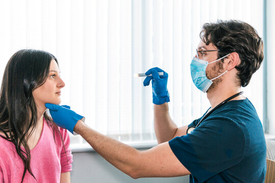 A healthcare worker in blue gloves is attentively taking a patient's temperature with a digital thermometer during a medical exam
