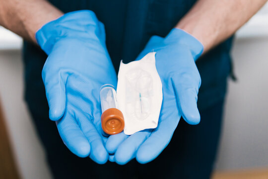 Close-up of anonymous gloved hands holding a sealed medical syringe and vial, ready for sterile medication administration