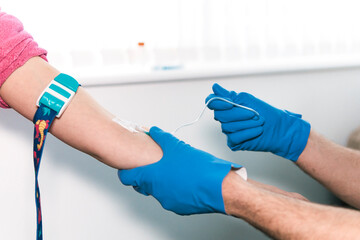 Focused healthcare anonymous professional adeptly inserts an IV catheter into a patient's vein during a medical procedure in a bright clinical setting