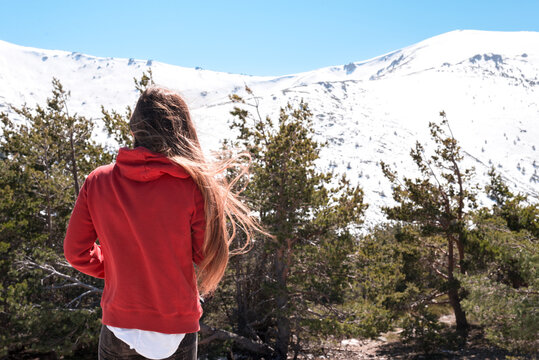 Woman in red hoodie admiring snowy mountain landscape