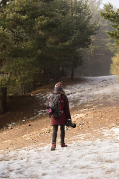 Female hiker with camera trekking snowy forest path