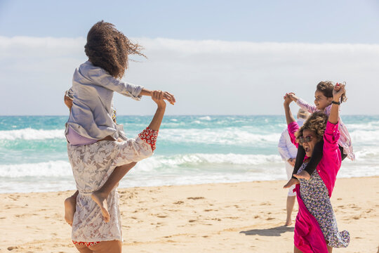Joyful family fun at the beach with kids on shoulders