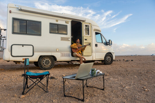 Nomadic Musician Composing by the Sea at Sunset