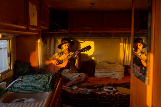 Nomadic musician composing in motorhome at sunset