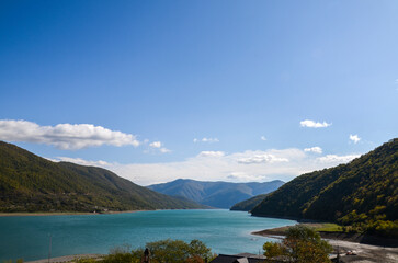 Breathtaking panoramic view of a calm water of the Zhinvali Water Reservoir nestled between lush green mountains under a clear blue sky from the Ananuri fortress complex, Georgia