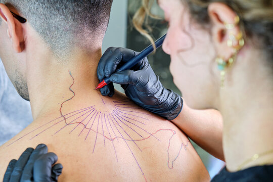 Tattoo artist at work in studio on male client