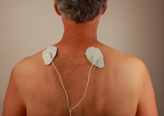 Man using an Electro Therapy Massager or Tens Unit on his back for pain relief of Muscles and Joint