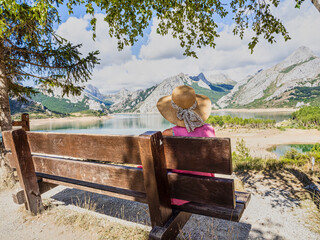 Tourist sitting on a bench contemplating the Riaño reservoir on a sunny summer, León province, Community of Castilla y León, Spain.