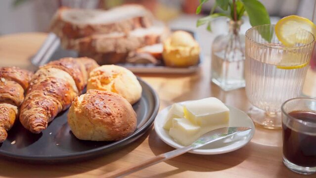 Continental breakfast set with homemade pancakes on a white plate and french pastry and bread and butter. 