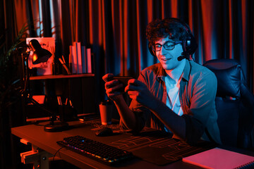 Smiling young gaming streamer team playing with Esport online on smartphone fighting wearing headphones at neon light room. Practising strategy plan to win competitors for next harder level. Gusher. - obrazy, fototapety, plakaty