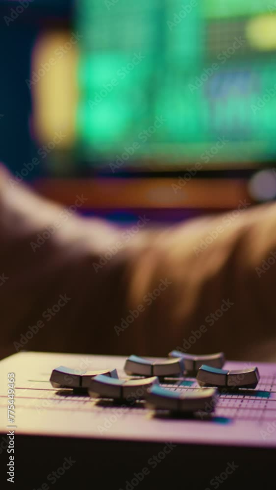 Poster vertical video sound engineer operating on motorized faders controller in professional studio, editi