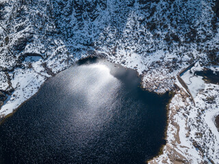 Aerial top down view of lake on Covão de Ferro Dam, surrounded by snow. Serra da Estrela Natural...