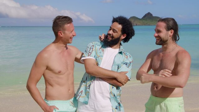 Young cheerful African American in Hawaiian shirt and two barechested Caucasian men in shorts posing over fascinating view of azure waters of the ocean. High quality 4k footage