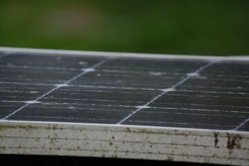 Macro of dirty solar panel unit, blurred green background