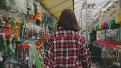 beautiful young woman in a garden supplies store. Girl looking for buying gardening tools