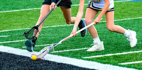 An offensive player with the ball is being chased by the defense. Girls varsity lacrosse game in...