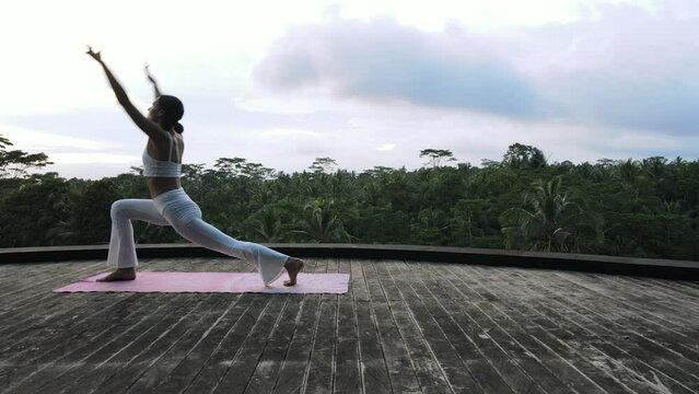 A beautiful young girl of European appearance, brunette, doing yoga, doing breathing exercises, in a stylish white yoga suit.