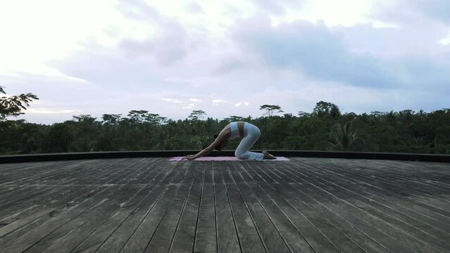 A beautiful young girl of European appearance, brunette, doing yoga, doing breathing exercises, in a stylish white yoga suit.