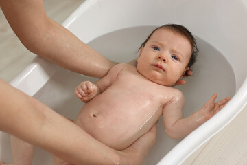 Mother bathing her little baby in bathtub, closeup