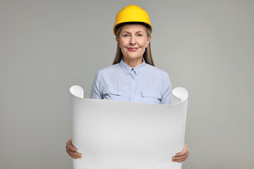 Architect in hard hat with draft on grey background