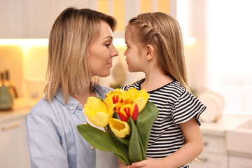 Obraz na płótnie Canvas Little daughter congratulating her mom with bouquet of beautiful tulips at home. Happy Mother's Day