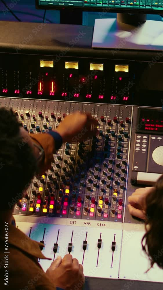 Fototapete vertical video music production team examining volume levels on audio software, using mixing and mas