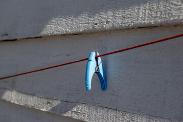 A single blue plastic clothespin clipped to a rusty brown cable. The outdoor laundry line is...