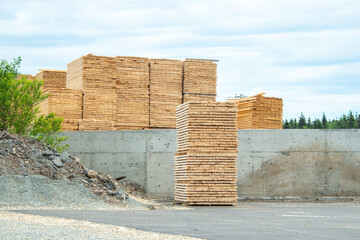 A lumber yard of a hardware store with bulk stacks of short-cut lumber, boards, and rough planks stockpiled for sale. The timber yard has spruce wood sawed for building materials and stacked for sale.