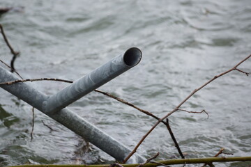 Macro of clutter of metal pipes and branches stuck in a river
