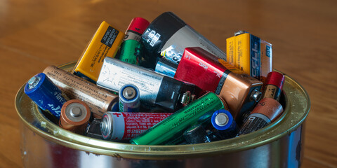 A tin can filled with household batteries. 
