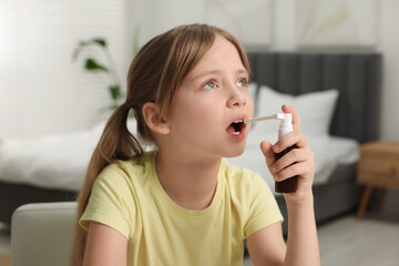 Little girl using throat spray at home