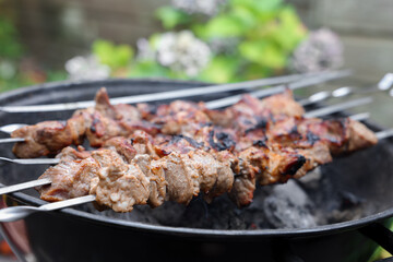 Cooking delicious kebab on metal brazier outdoors, closeup