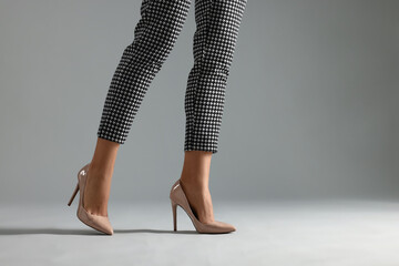 Obraz premium Businesswoman in beige shoes on grey background, closeup