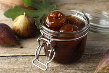 Jar of tasty sweet jam and fresh figs on wooden table