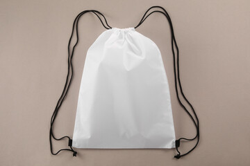 One white drawstring bag on beige background, top view
