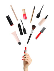 Woman holding red lipstick as magic wand making other decorative cosmetics flying on white...