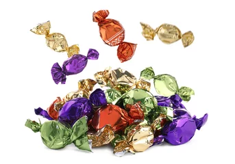  Candies in bright wrappers falling onto heap against white background © New Africa