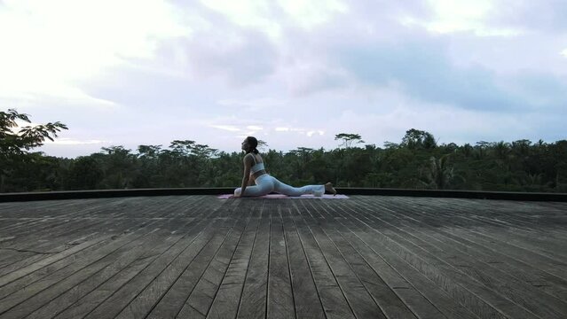 A beautiful young girl of European appearance, brunette, doing yoga, doing breathing exercises, in a stylish white yoga suit.