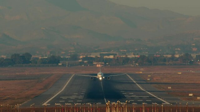 Airplane taking off from a runway with mountainous terrain in the background