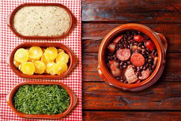 Brazilian feijoada, traditional food from Brazil cuisine, on ceramic casserole bowl, over rustic wooden table