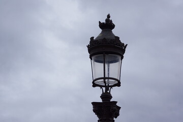 Fototapeta na wymiar Antique black street lamp under cloudy sky