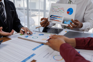 Group of confident business people point to graphs and charts to analyze market data, balance...