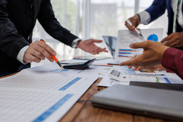 Group of confident business people point to graphs and charts to analyze market data, balance sheet, account, net profit to plan new sales strategies to increase production capacity.	