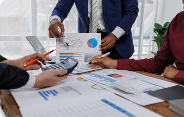 Group of confident business people point to graphs and charts to analyze market data, balance sheet, account, net profit to plan new sales strategies to increase production capacity.	