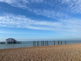 Pier in calm blue water under summer sky at Brighton in Sussex, England. Ruin of west pier on sunny...
