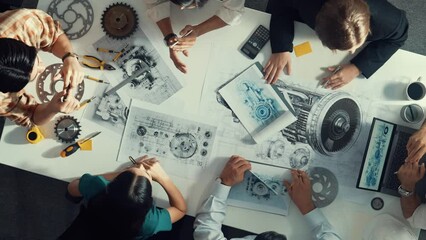 Top down aerial view of smart engineer team working together to design turbine engine. Professional technician discussing about jet engine construction while pointing at part of engine. Alimentation.