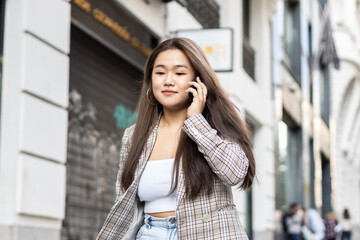Fototapeta premium Young asian woman talking on the phone in the city