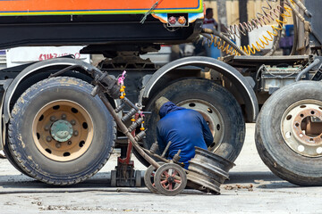 A man is changing a wheel on a truck, Thailand