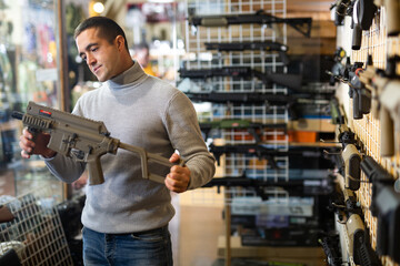 Man chooses semi-automatic pneumatic assault rifle at a gun store