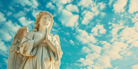 A white angel statue stands tall against a blue sky backdrop, exuding a sense of tranquility